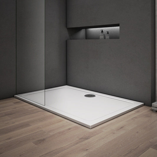 A white, square-shaped shower tray with a low profile design, installed on a wooden floor within a modern bathroom setting.